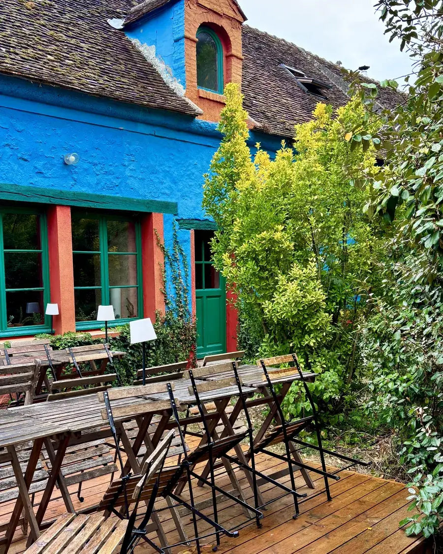 La maison bleue de la ferme, lucarne orange et fenêtres vertes, terrasse en bois