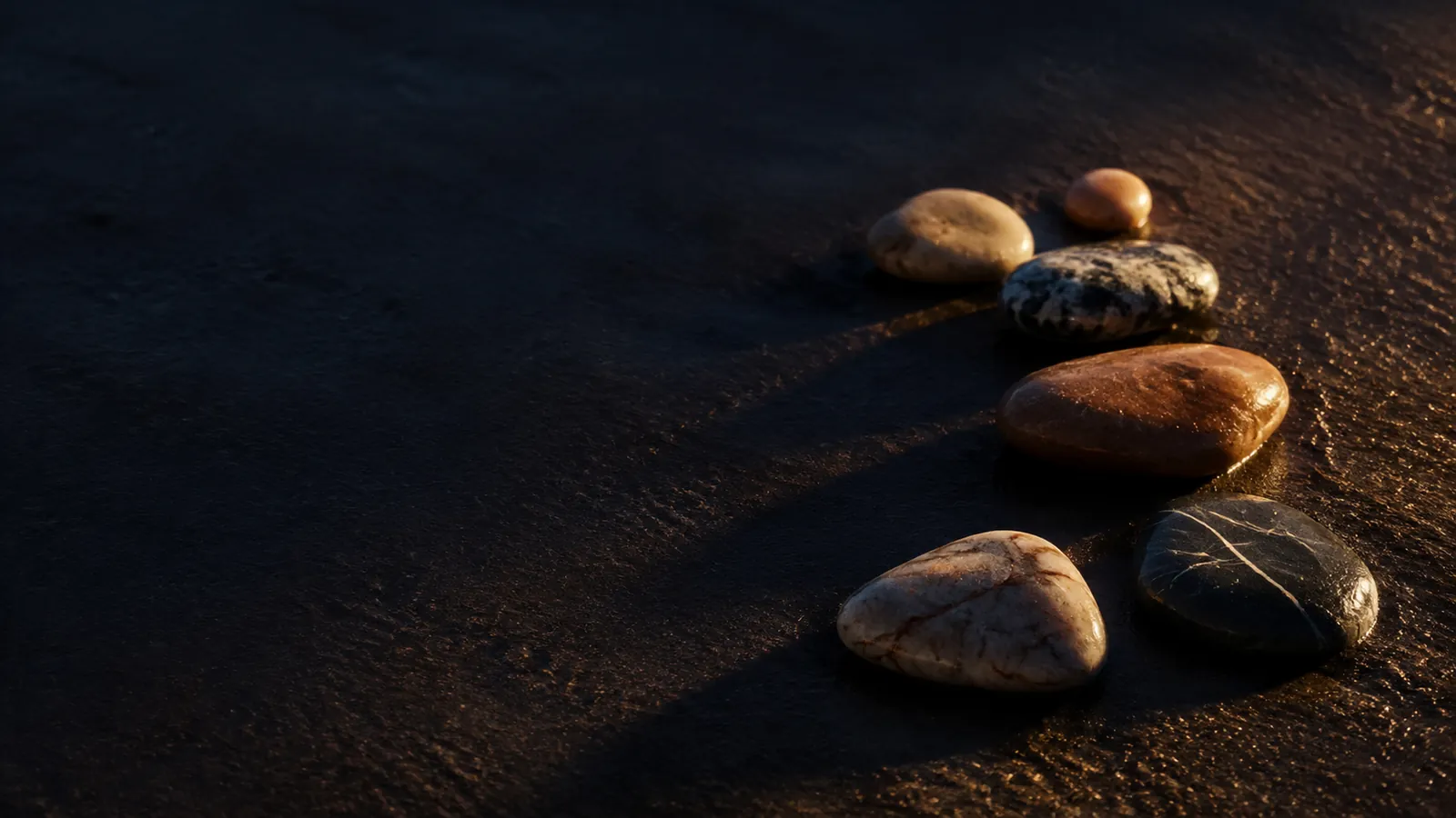Galets alignés sur le sable humide, image du stage de tantra pour célibataires